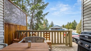 A wooden deck with a grill, a table, and chairs.