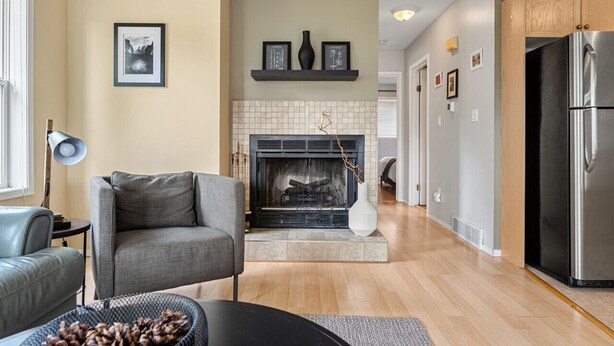 A modern living room with a fireplace, a grey sofa, and a dining table with a basket of pinecones.