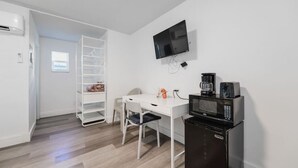 A small kitchenette with a microwave, coffee maker, and a TV mounted on the wall.