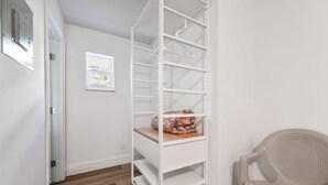 A hallway with a white closet, a chair, and a window.