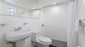 Un baño con lavamanos, inodoro y ducha blancos.