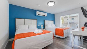 Una habitación de hotel con dos camas, un escritorio y una ventana con persianas.