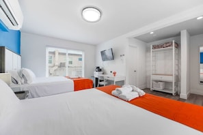 A hotel room with two beds, a desk, a TV, and a wardrobe.