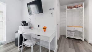 Una habitación moderna y blanca con un escritorio, una silla y un televisor montado en la pared.