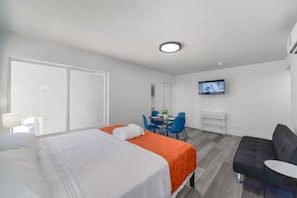 A hotel room with a bed, a desk, a chair, a TV, and a sofa.