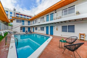 Un'area piscina con una piscina blu cristallina, un piccolo tavolo con una pianta e due poltrona relax.
