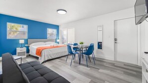 Una camera d'albergo moderna con un letto, una scrivania, una sedia e una televisione.