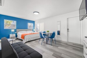 Une chambre d’hôtel moderne équipée d’un lit, d’un bureau, d’une chaise et d’un téléviseur.
