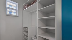 A white closet with open shelves and a hanging basket.