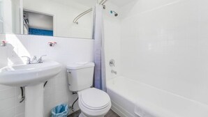 Un baño con lavamanos, inodoro y bañera blancos.