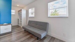 Una sala de estar moderna con un sofá gris, un mueble de entretenimiento blanco y estanterías empotradas.
