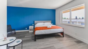 Habitación de hotel moderna con una cama grande, un escritorio pequeño, una silla y una ventana con vistas al exterior.