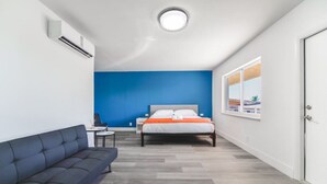 Una habitación de hotel moderna con cama, sofá, una mesita y ventana con vistas.
