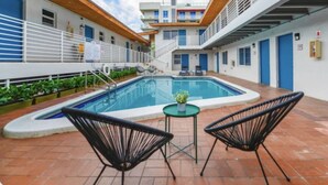 A swimming pool with two chairs, a small table, and a potted plant.