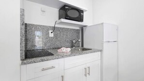 A kitchen with granite countertops, a stainless steel sink, a microwave, and a white refrigerator.