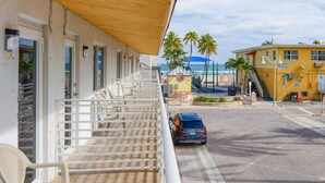 A hotel with a balcony, outdoor seating, and a view of the beach and ocean.