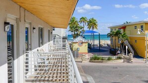 Ein Hotel direkt am Strand mit einem hölzernen Balkon, einem kleinen Glockenturm und Blick auf den Ozean.