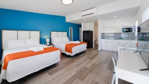 Una habitación de hotel moderna con dos camas, kitchenette y baño.