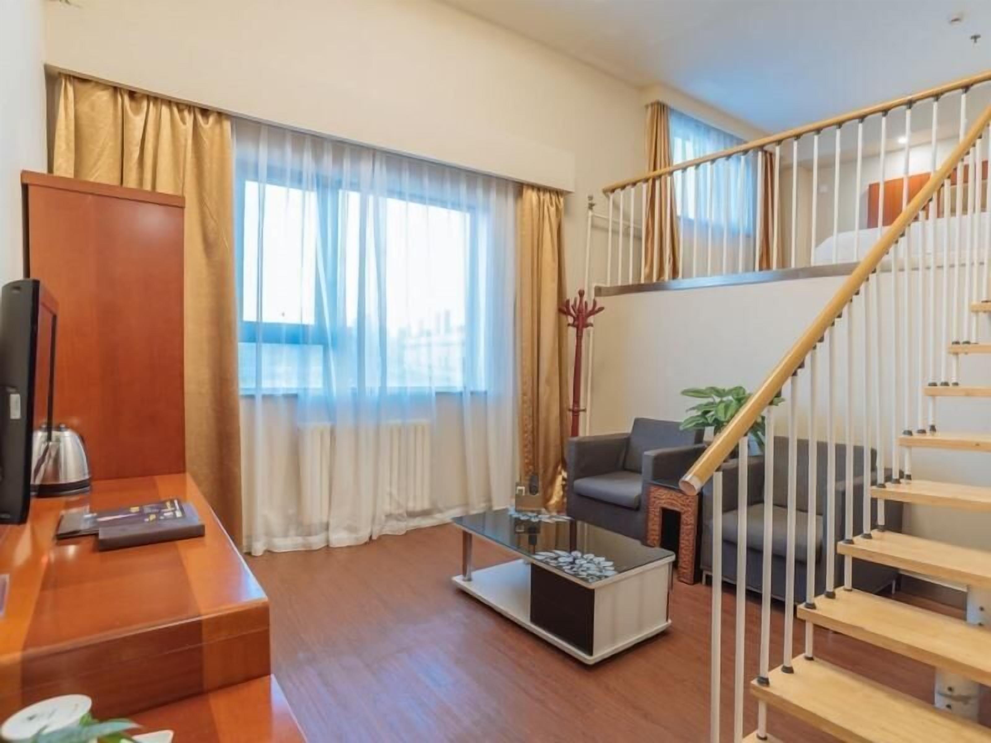 Una sala de estar moderna con una escalera de madera, una mesa de centro de vidrio y un sofá.