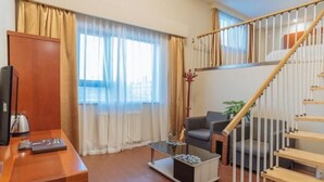 A modern living room with a wooden staircase, a glass coffee table, and a sofa. - Greentree Inn Beijing Chaoyang District Happy Valley Express Hotel (Beijing)