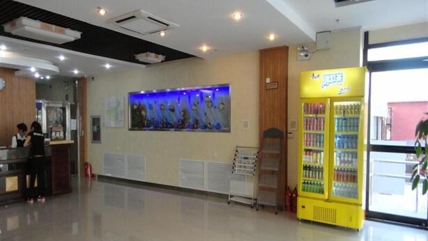 A hotel lobby with a reception desk, a wall-mounted artwork, a vending machine, and a window with a view. - Greentree Inn Beijing Chaoyang District Happy Valley Express Hotel (Beijing)