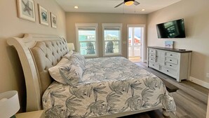 Una camera da letto con un letto grande, una ventola a soffitto, una TV e vista all'esterno.