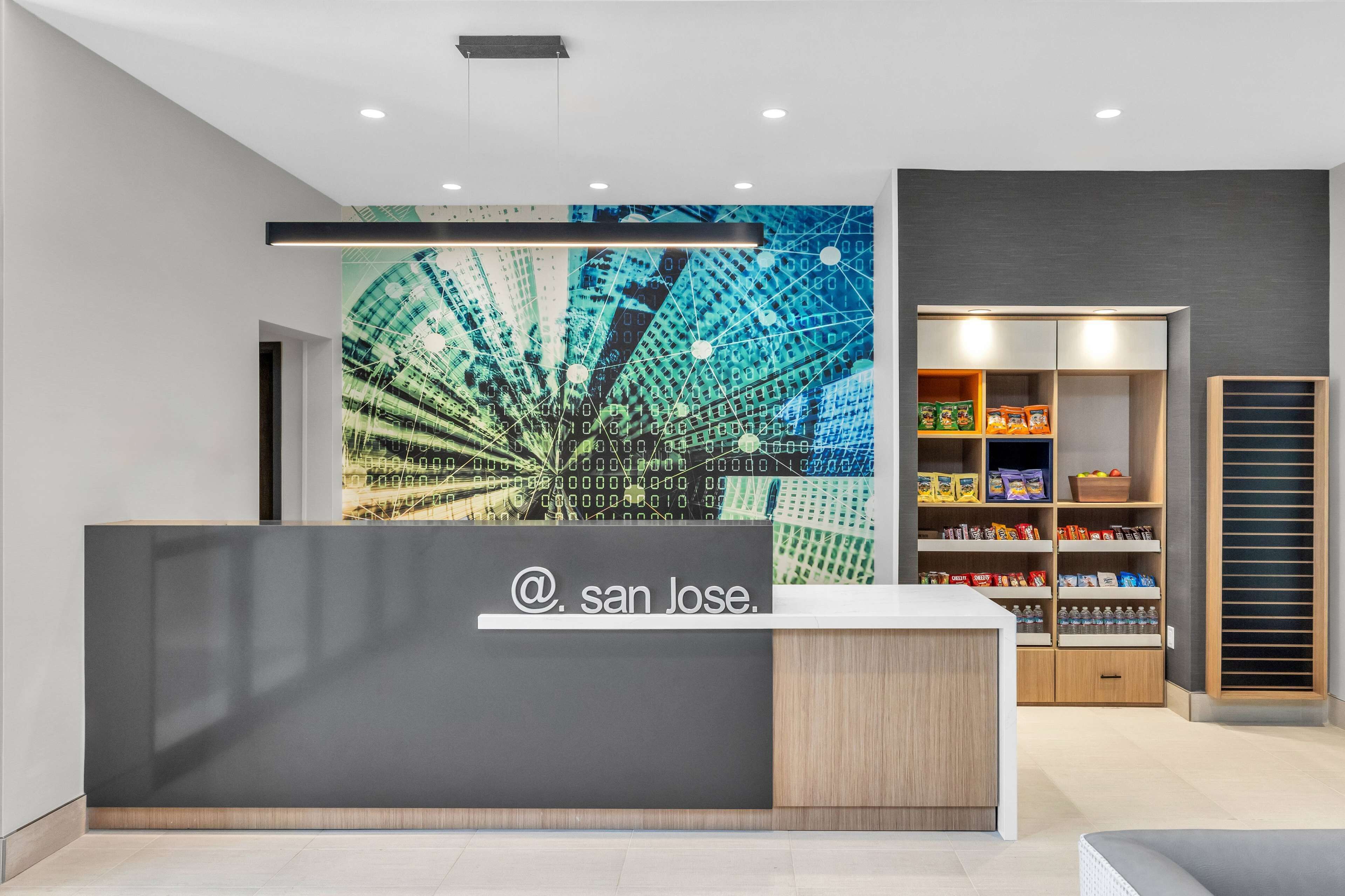 A reception area with a modern design, including a digital art wall, a reception desk, and a storage cabinet with snacks.