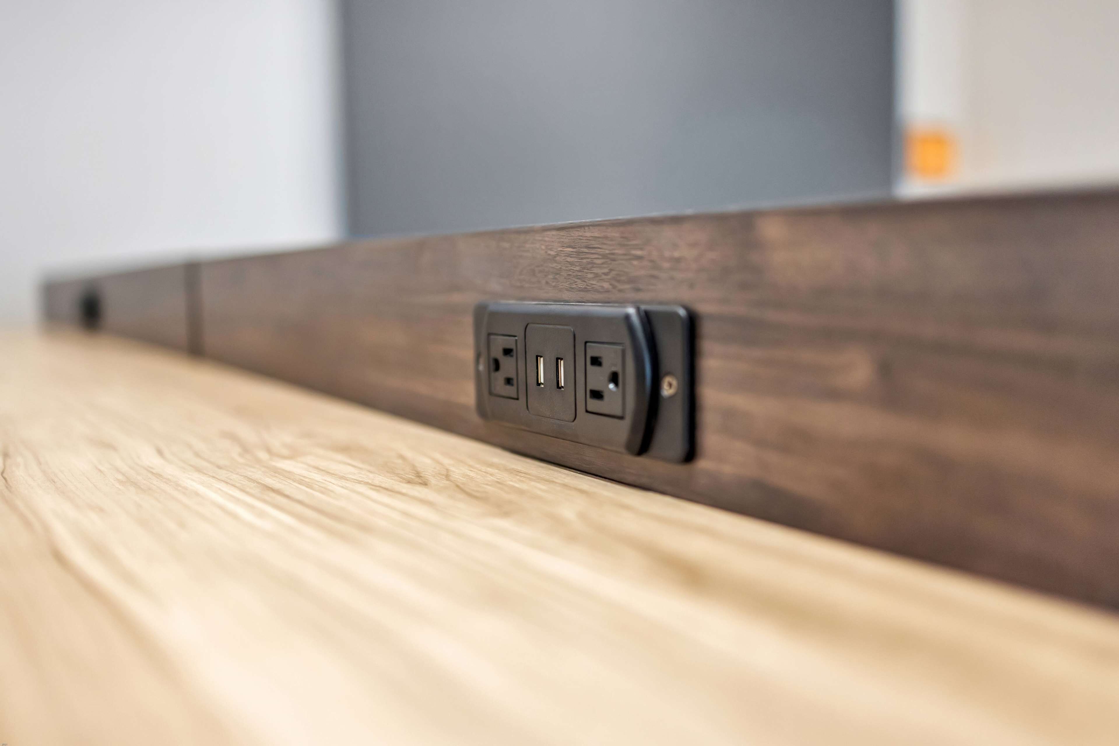 A close-up of a wall socket on a wooden surface.