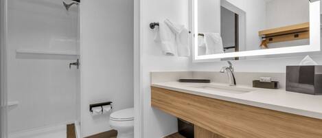 A modern bathroom with a glass shower enclosure, a toilet, a sink with a mirror, and a towel rack.