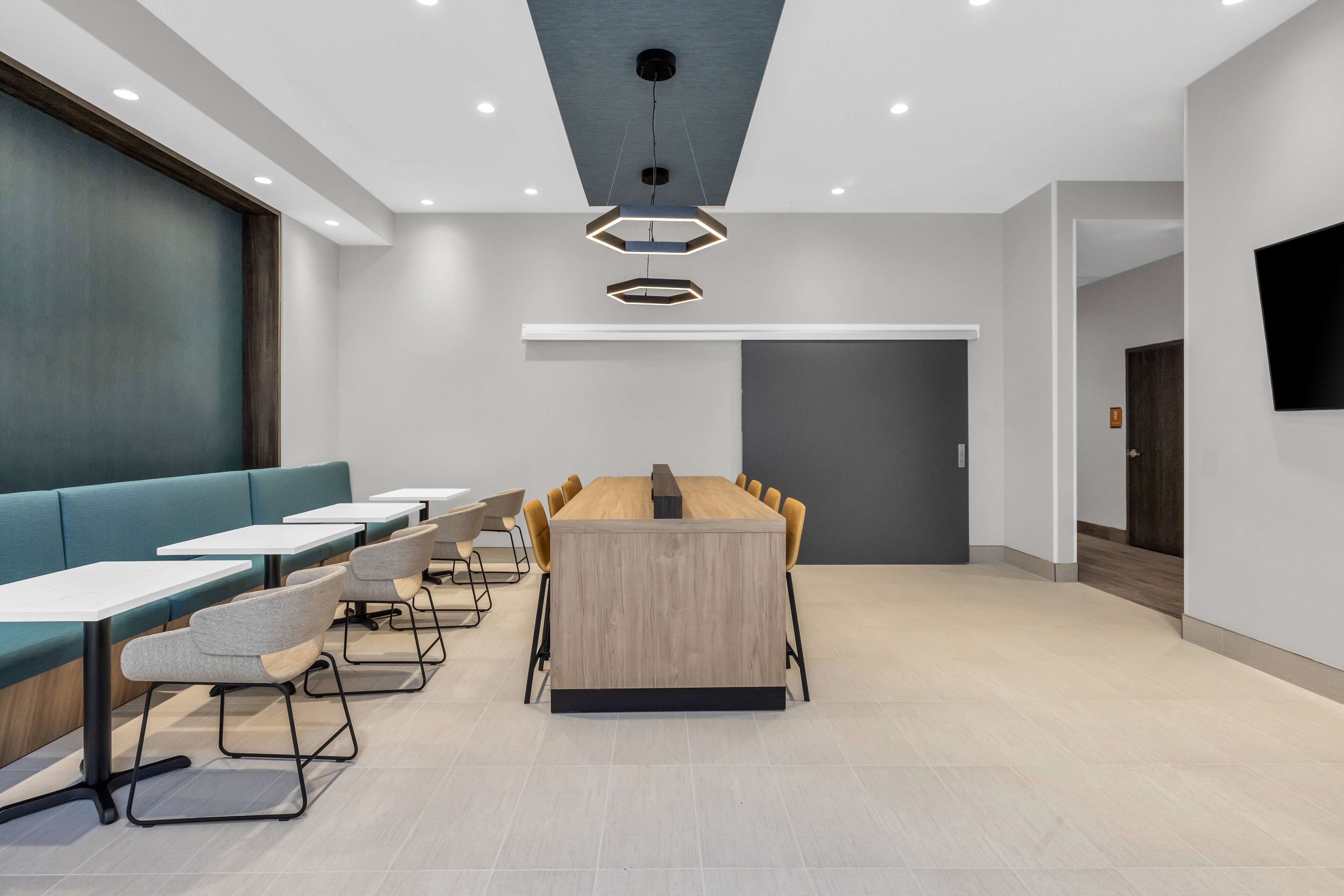 A modern conference room with a long table, chairs, and a seating area with tables and chairs.