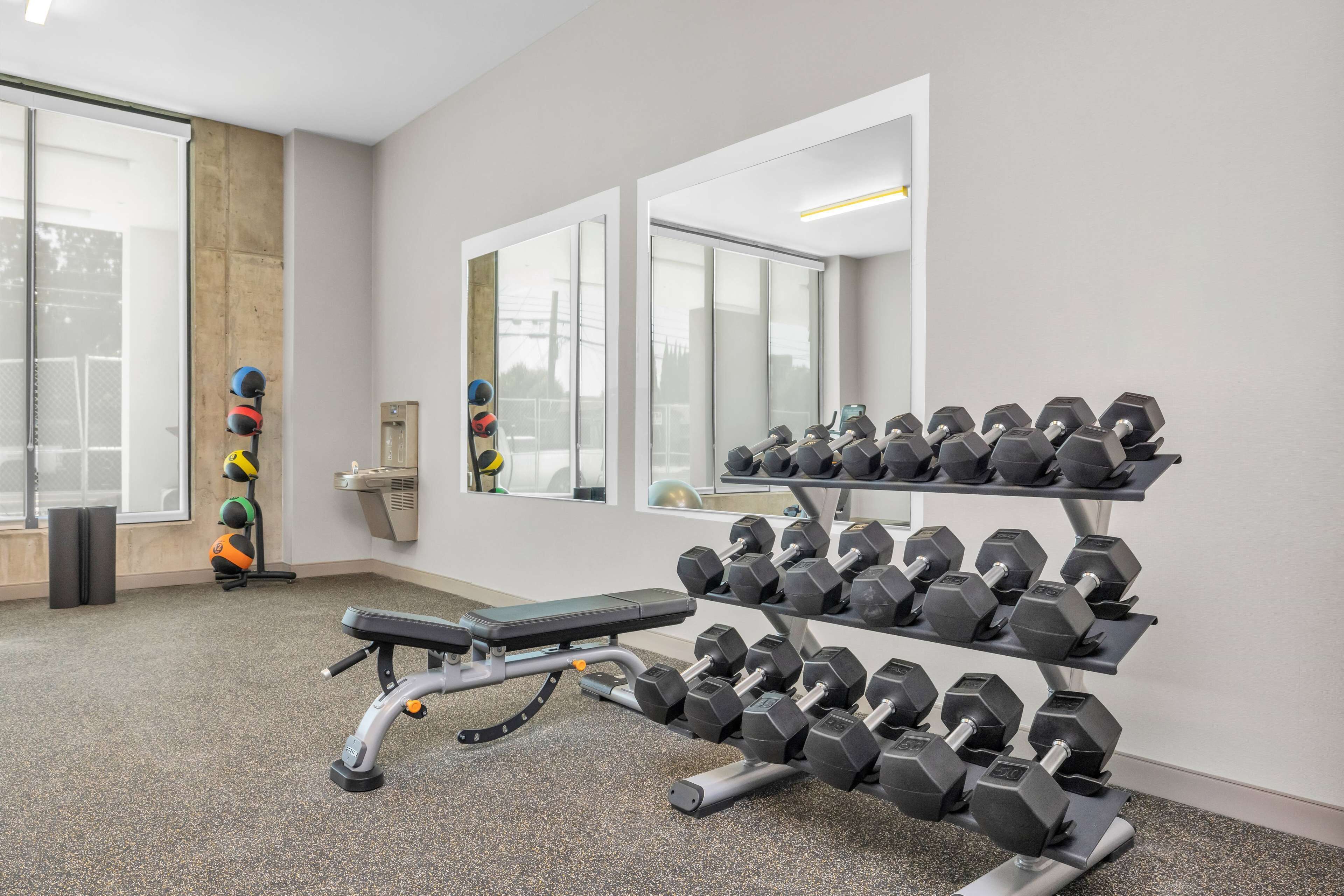A gym with a bench, dumbbells, and exercise balls.