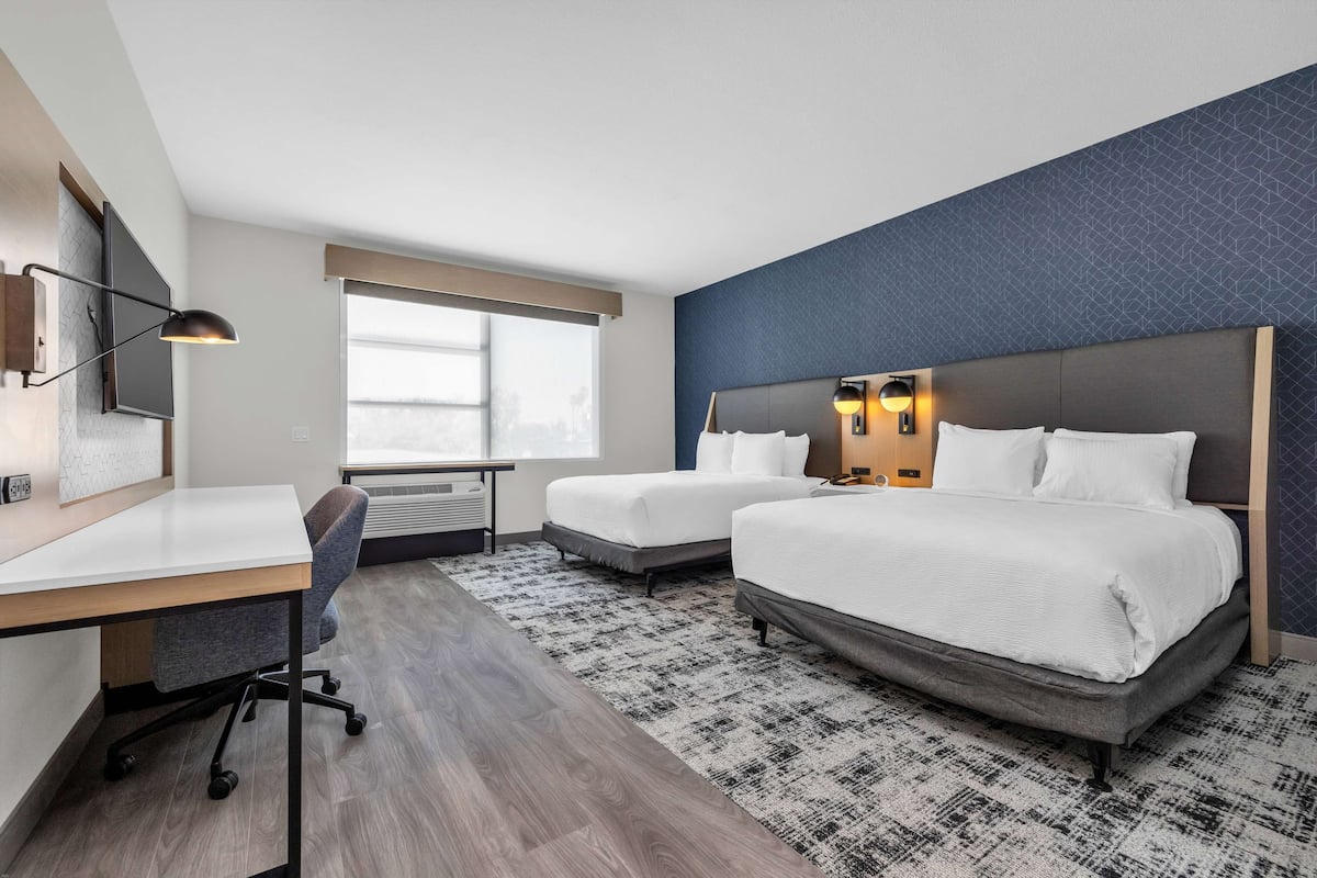 Une chambre d’hôtel avec deux lits, un bureau et une chaise.