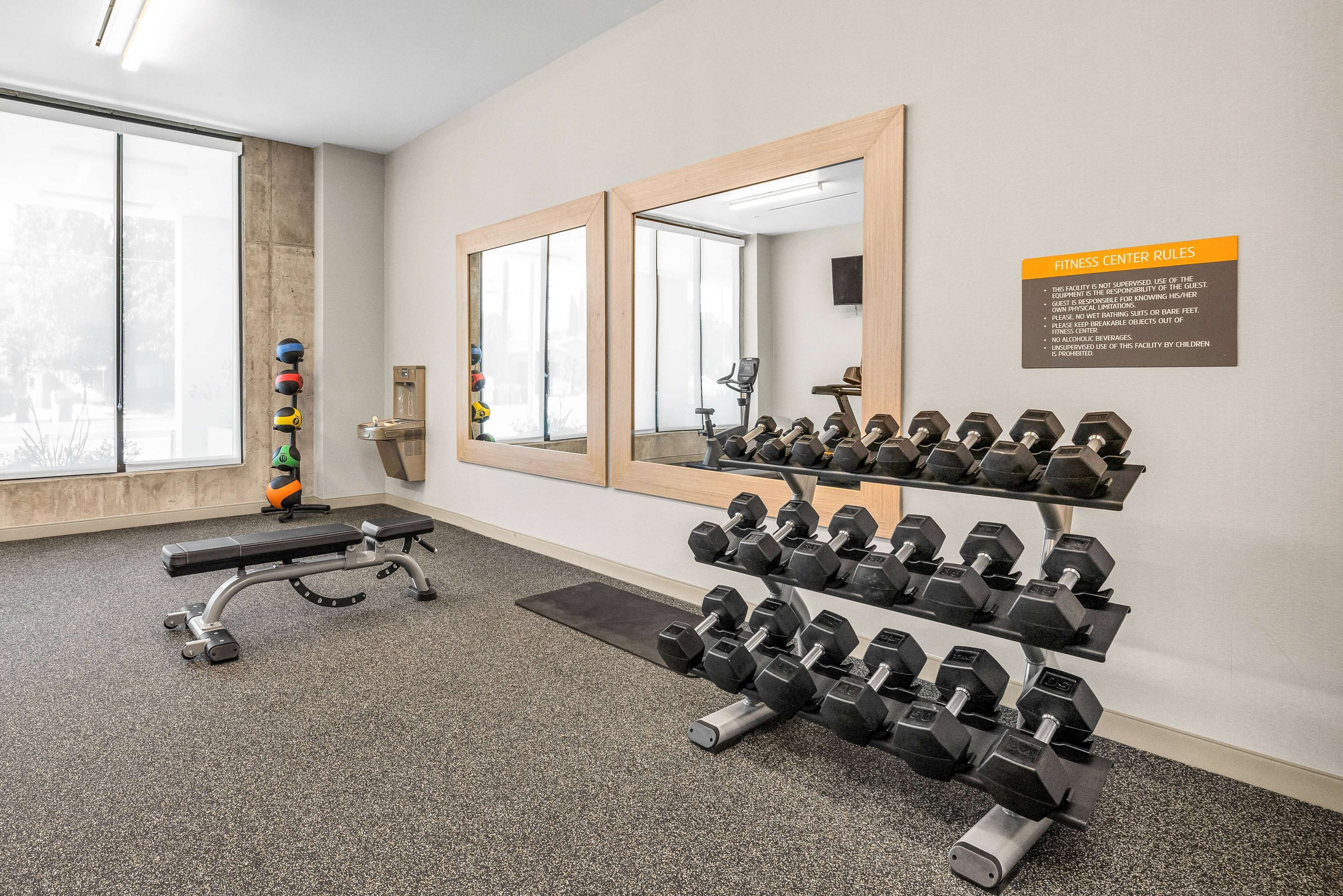 Een fitnessruimte met een bankje, gewichten en een spiegel.