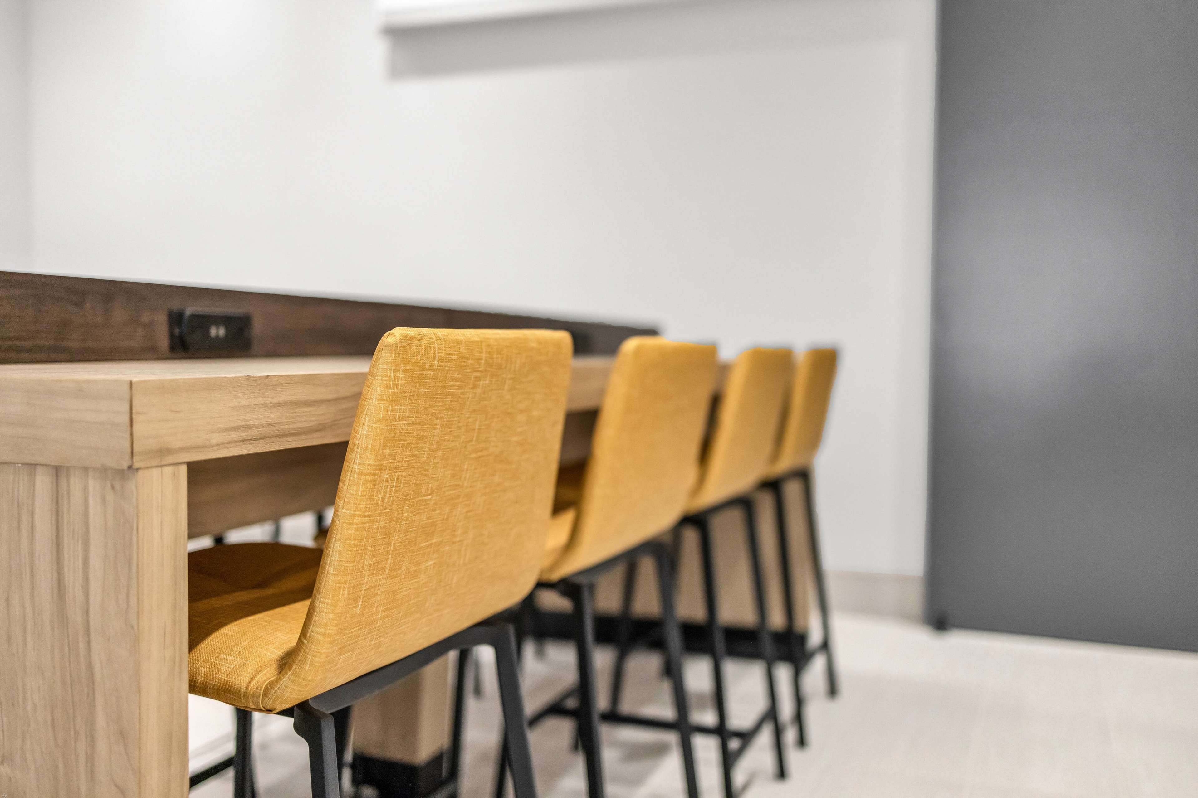 Een vergadertafel met vier stoelen, een houten blad en zwarte poten.