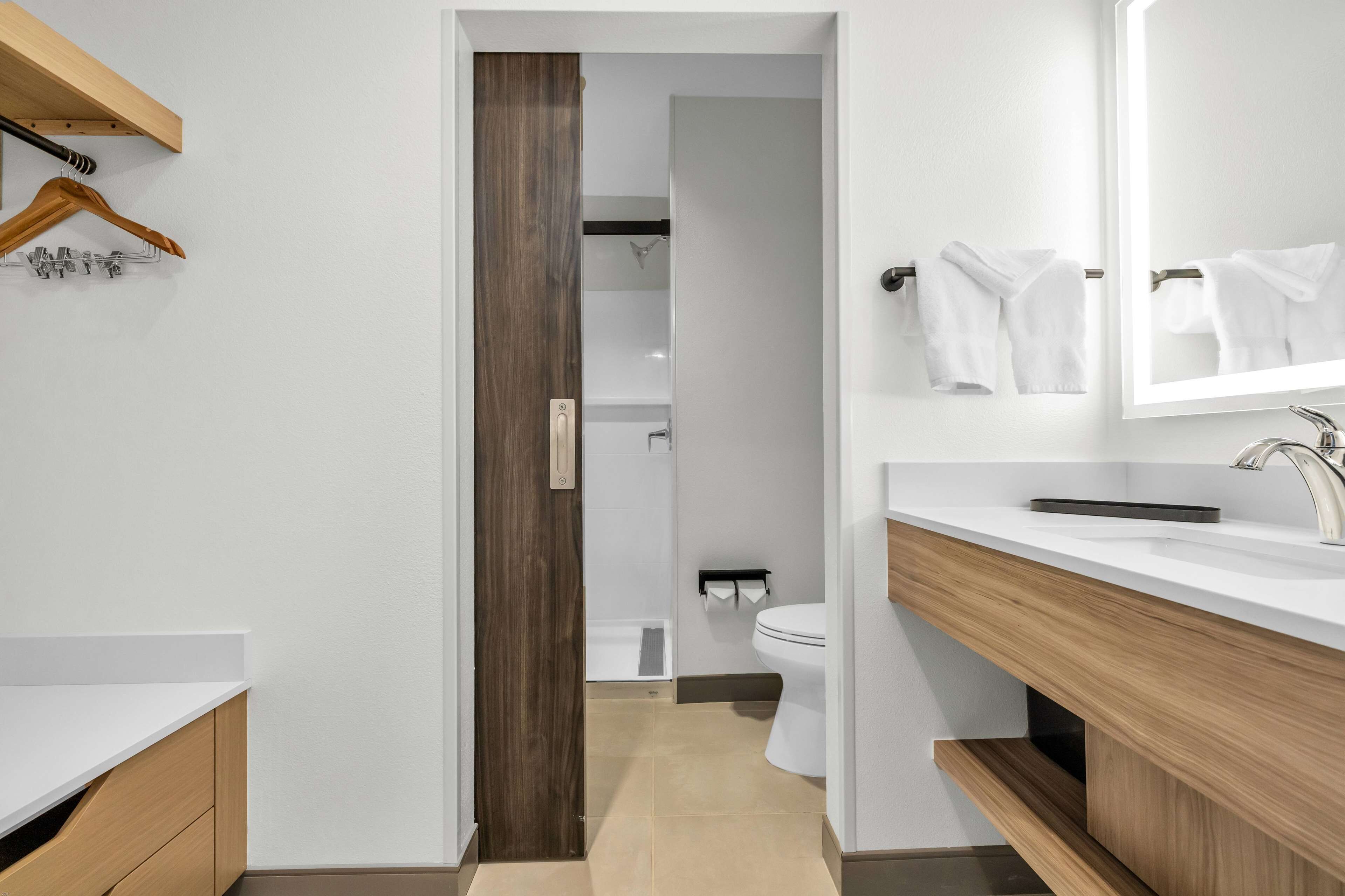 Un baño moderno con un lavamanos blanco, tocador de madera y un espejo.