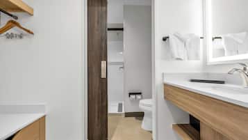 Un baño moderno con un lavamanos blanco, tocador de madera y un espejo.