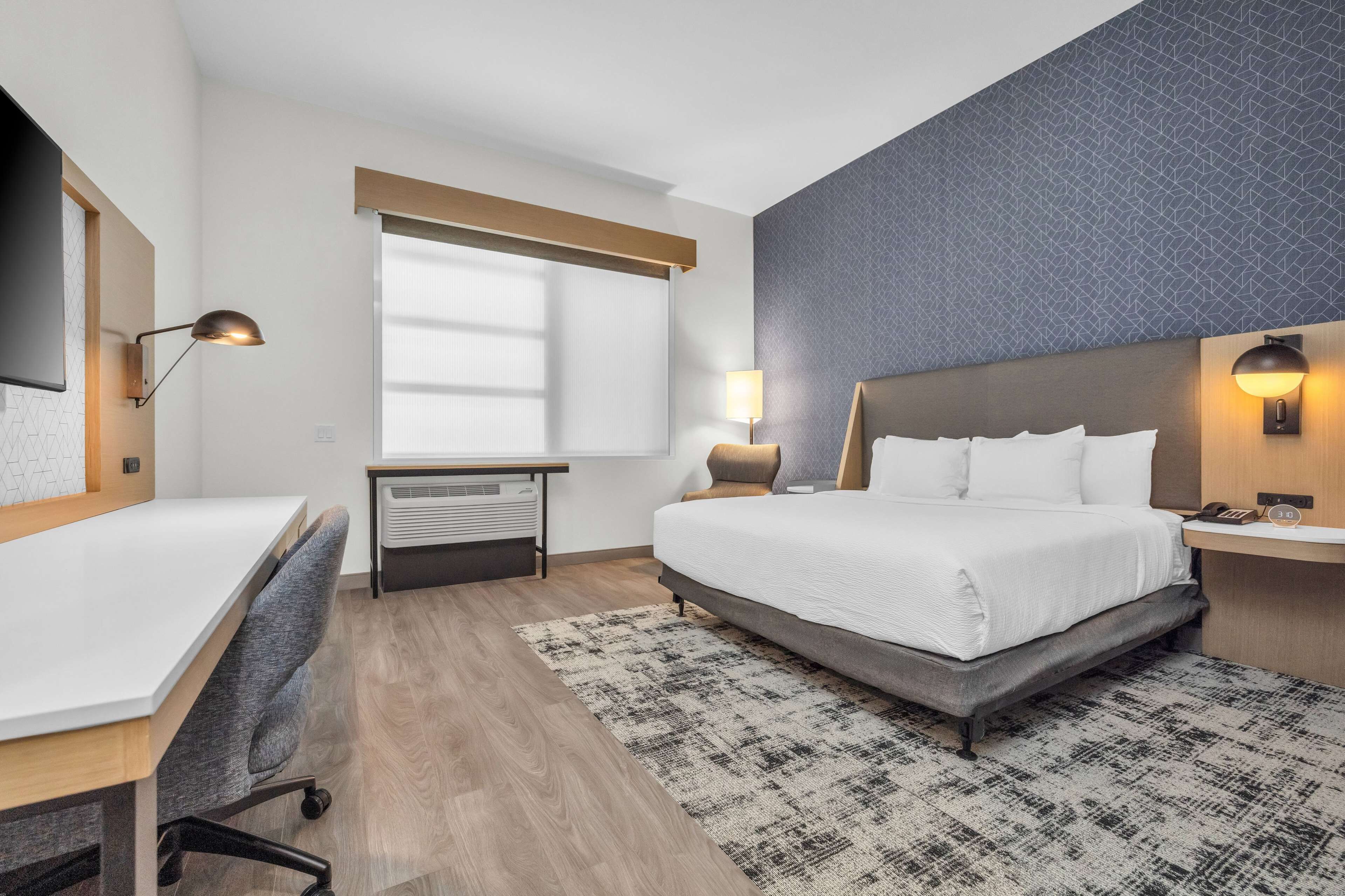 Ein Hotelzimmer mit Bett, Schreibtisch und zwei Nachttischlampen.