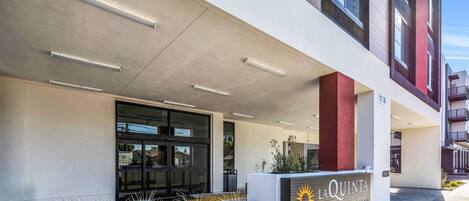 A modern building with a prominent entrance, large windows, and a sign reading "LA QUINTA BY WILLOW TREE".