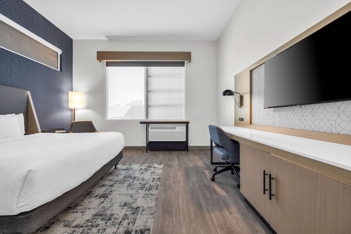 Une chambre d’hôtel avec un lit, un bureau, une télévision et une fenêtre.