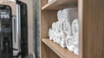 Neatly stacked white towels on wooden shelves in a hotel room.