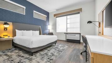 Une chambre d’hôtel moderne, dotée d’un grand lit, d’un bureau et d’une fenêtre avec stores.