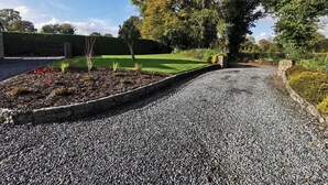 A gravel driveway leading to a green lawn area with a stone wall and a hedge. - Perfect Country Retreat, Kildare Cottage 1000 (Suncroft)