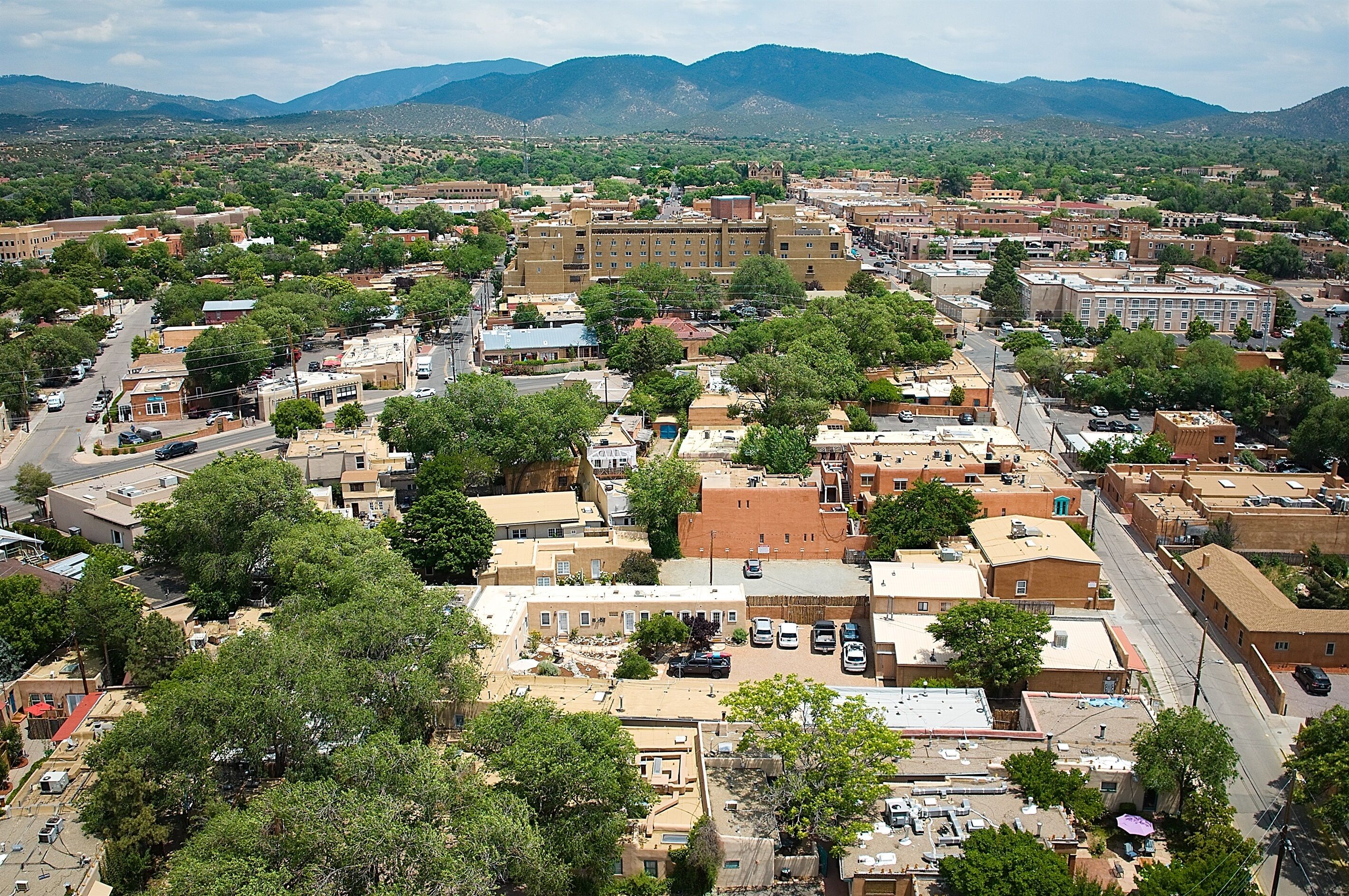 An aerial view of a town with buildings, streets, and mountains in the background.