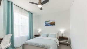 A bedroom with a bed, two bedside tables with lamps, a desk with a chair, a ceiling fan, and a window with curtains. - Luxury Brand New Townhouse, family and pet friendly (Highlands Ranch)