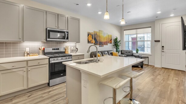A modern kitchen with a central island, stainless steel appliances, and pendant lighting. - Luxury Brand New Townhouse, family and pet friendly (Highlands Ranch)