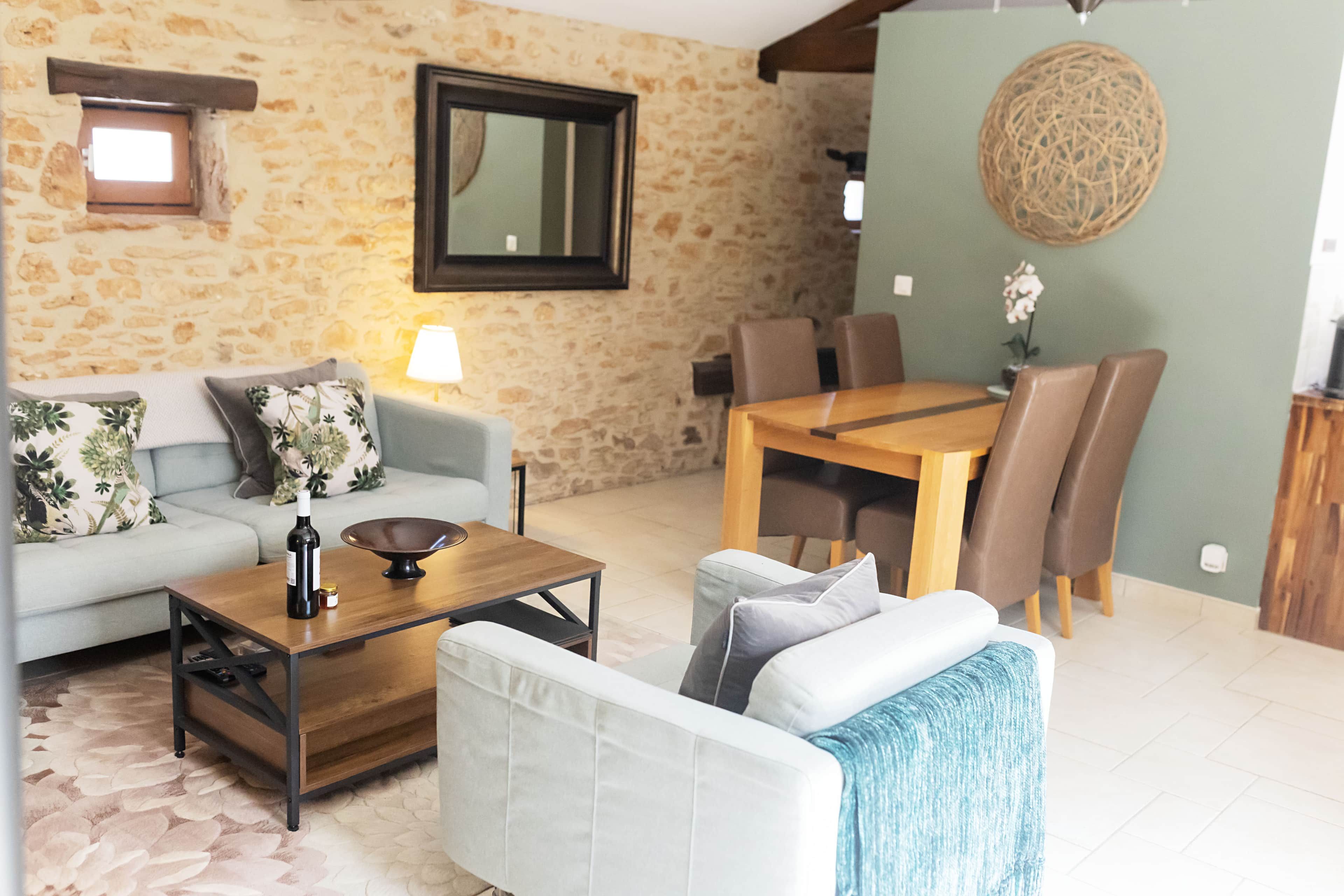 Een woonkamer met een bank, salontafel en een eettafel met stoelen.