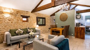 Una sala de estar con una pared de piedra, un sofá, una mesa de centro y un comedor con una mesa y sillas de madera.