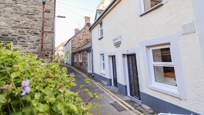 A narrow street lined with traditional stone and plaster buildings, featuring a mix of residential and commercial properties. - Deu-ddrws (Barmouth)