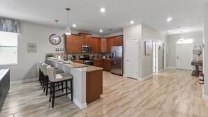 A modern kitchen with wooden cabinets, a stainless steel refrigerator, and a granite countertop. - 5 Star Villa With 9 Bedrooms, Orlando Villa 4227 (Davenport)