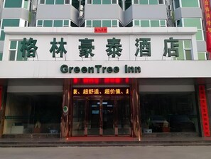 A hotel entrance with a sign reading 'GreenTree Inn' and Chinese characters above it.